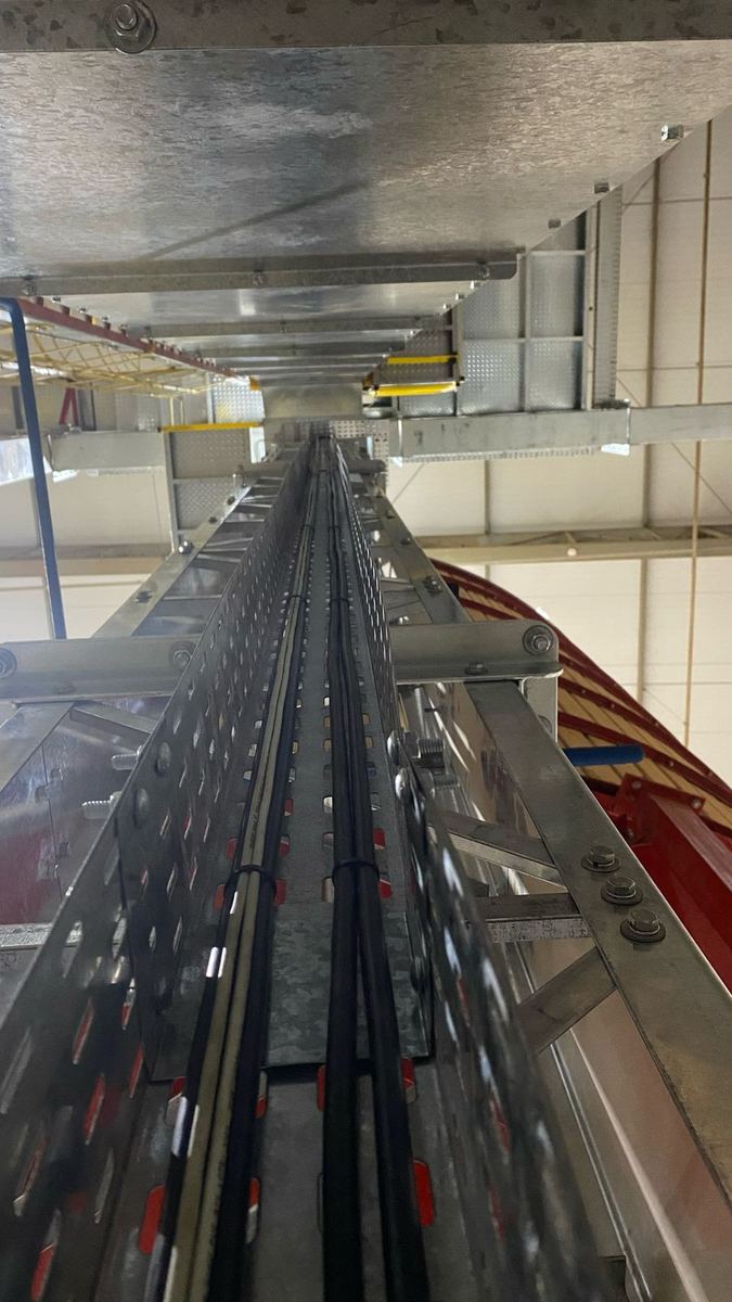 Eletrocalha perfurada vertical com cabos lançados em estrutura industrial